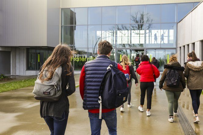 lycéens de dos marchent vers l'entrée de l'établissement 