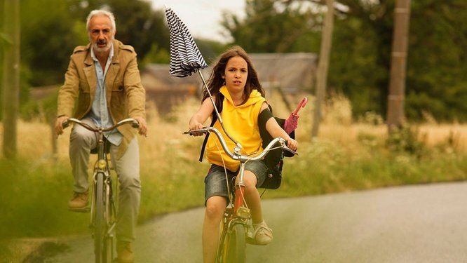 image du film : une petite fille et un homme à vélo sur une route de campagne