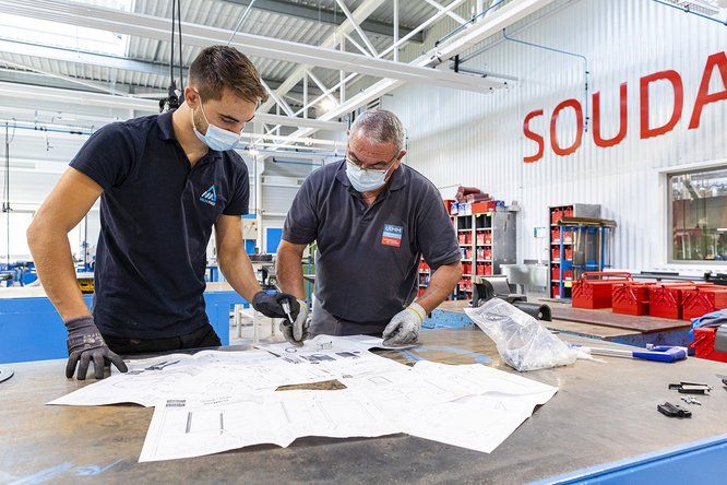 Un homme âgé et son jeune apprenti consultent des plans 